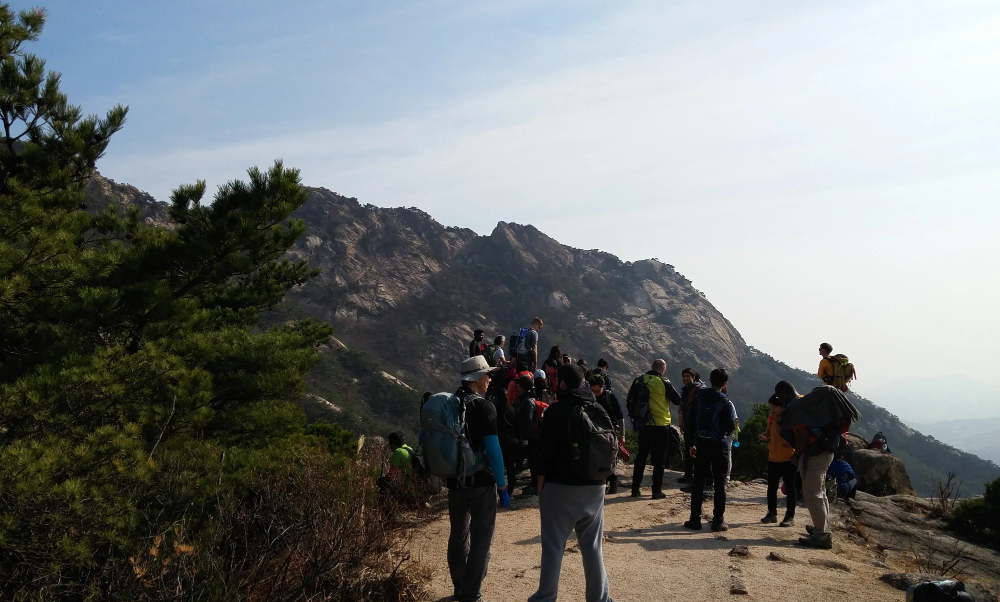 Hikers with backpacks pause among pine trees and granite ridges in Bukhansan National Park